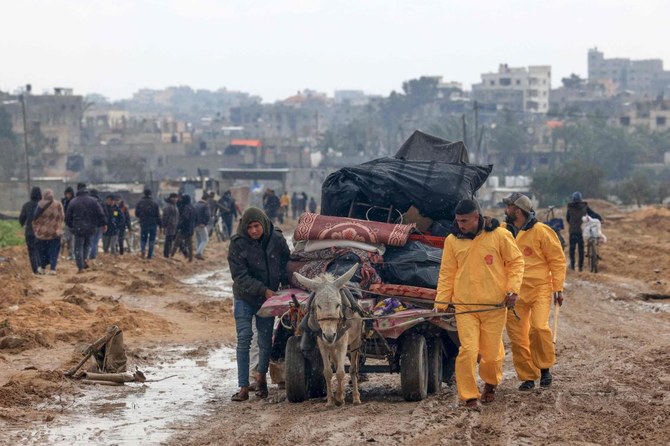 Palestinians, some wearing Hazmat suits left over from the Coronavirus pandemic to keep warm, transport some of their belongings as the flee Khan Yunis in the southern Gaza Strip further south on Feb. 2, 2024. (AFP)