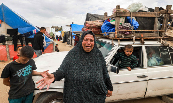 A woman reacts as she stands before a vehicle loaded with items secured by rope as people flee from Rafah in the southern Gaza Strip on February 13, 2024 north towards the centre of the Palestinian territory amid the ongoing conflict between Israel and the Palestinian militant group Hamas. (AFP)