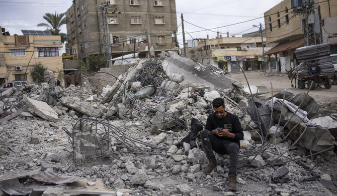 Ibrahim Hasouna, right, the sole survivor among his family, stands in front of the rubble of his family house with his friends, in Rafah, southern Gaza Strip, Tuesday, Feb. 13, 2024. (AP)