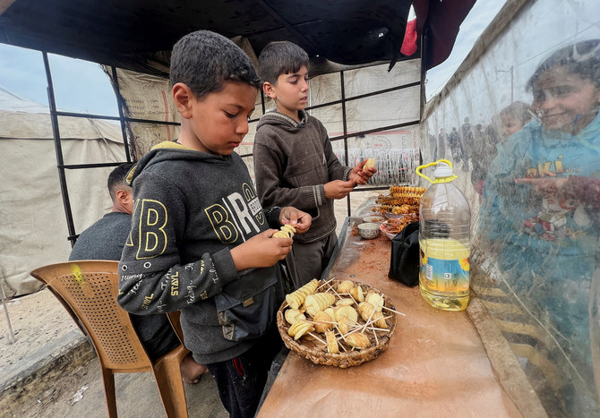 Displaced Palestinian boys sell homemade potato chips outside a tent camp in Rafah in the southern Gaza Strip, February 13, 2024. (Reuters)