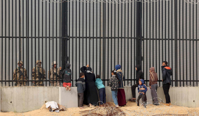 Displaced Palestinians talk to Egyptian soldiers at the border fence between Gaza and Egypt, on February 16, 2024 in Rafah, in the southern Gaza Strip, amid the ongoing conflict between Israel and the Palestinian Hamas militant group. (AFP)