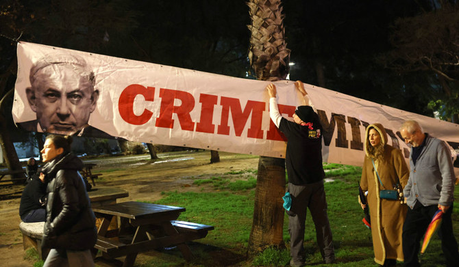 A protester hangs a banner during an anti-government demonstration in Israel's central city of Tel Aviv, on February 17, 2024, amid the ongoing conflict in the Gaza Strip between Israel and the Palestinian militant Hamas movement. (AFP)