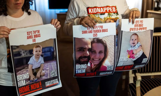 Ofri Bibas Levy, whose brother Yarden (34) was taken hostage with his wife Shiri (32) and two children Kfir (10 months) and Ariel (4), holds with her friend Tal Ulus pictures of them during an interview with Reuters, as the conflict between Israel and Hamas continues, in Geneva, Switzerland. (Reuters)