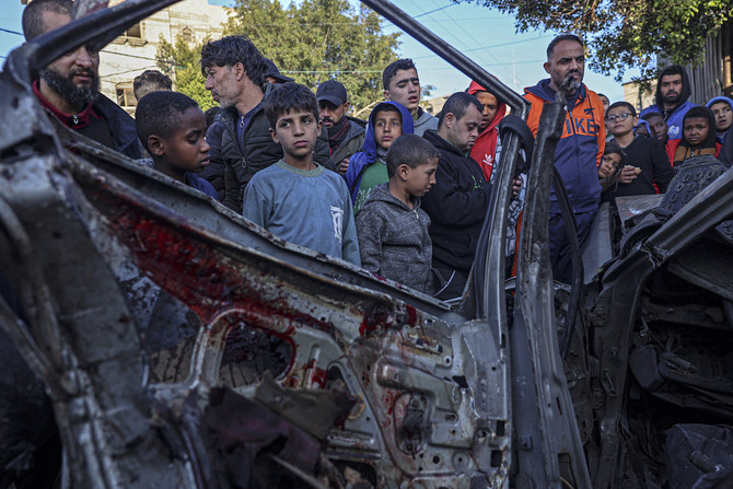 Onlookers gather around a car that was destroyed in an Israeli raid in Rafah in the southern Gaza Strip. (File/AFP)