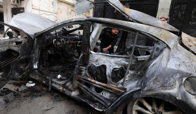 A child walks behind a car destroyed in an overnight Israeli strike on Jenin in the occupied West Bank, killing two men on February 23, 2024. (AFP)