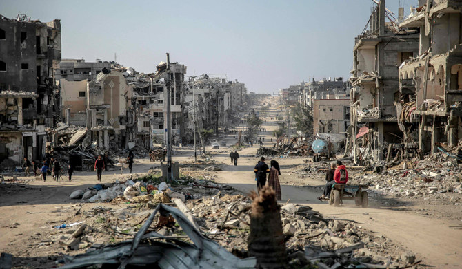 Palestinians walk past buildings destroyed during Israeli strikes in Beit Lahia in northern Gaza, on February 26, 2024, amid continuing battles between Israel and the Palestinian militant group Hamas. (AFP)