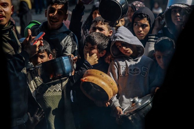 Palestinian children wait to get food from an aid distribution team in Beit Lahia, northern Gaza, on Feb. 26, 2024. (AFP)