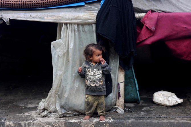 A displaced Palestinian child stands outside a makeshift tent attached to a school hosting families from other parts of the Gaza Strip in the Rafah refugee camp in southern Gaza on February 26, 2024, as battles between Israel and Hamas continue for the fifth month. (AFP)