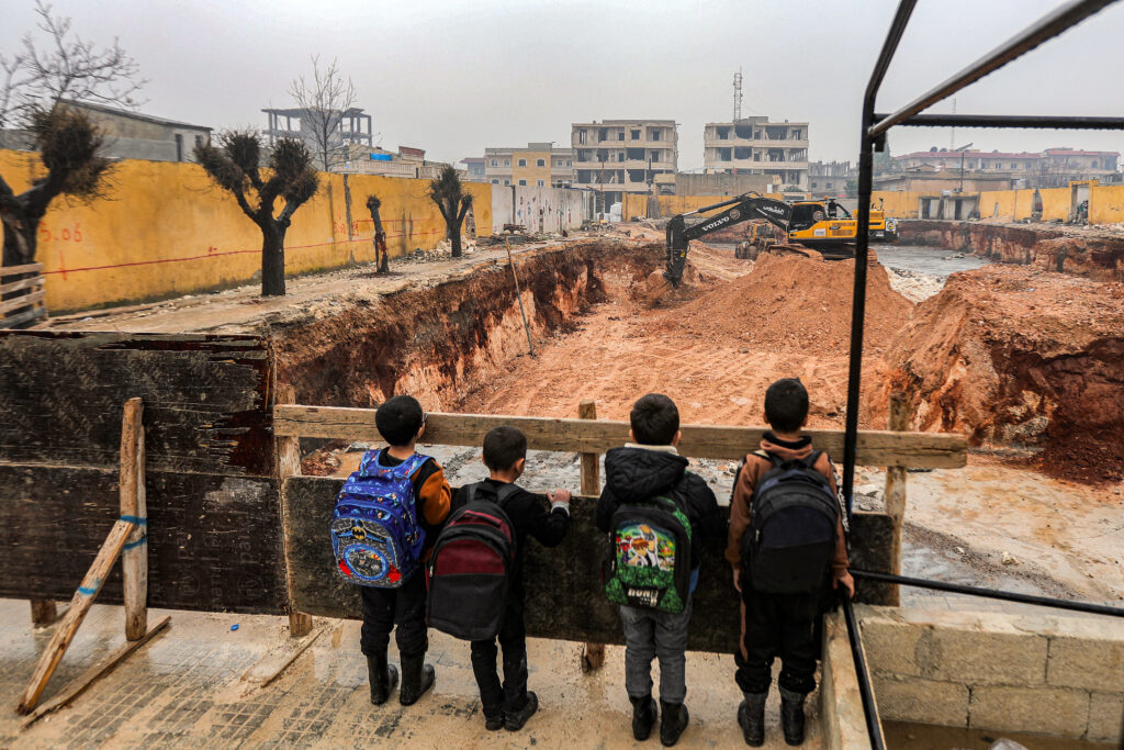 Children on their way to school at a make-shift facility stand to view the school's reconstruction site, in the town of Jindayris in the northwest of Syria's Aleppo province on February 3, 2024. (AFP)