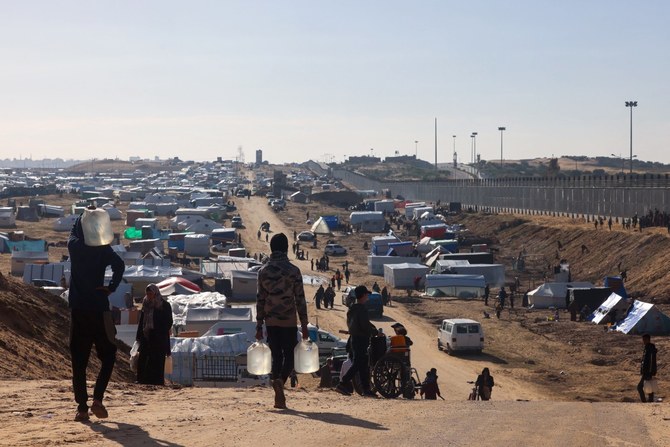 People ferry water at a makeshift tent camp for displaced Palestinians in Rafah near the border with Egypt in the southern Gaza Strip, on January 24, 2024 amid the ongoing conflict between Israel and the Palestinian militant group Hamas (AFP)