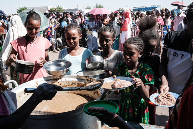 Sudanese people who fled the conflict in Geneina in Sudan's Darfur region, receive food from Red Cross volunteers in Ourang on the outskirts of Adre, Chad. (Reuters/File)