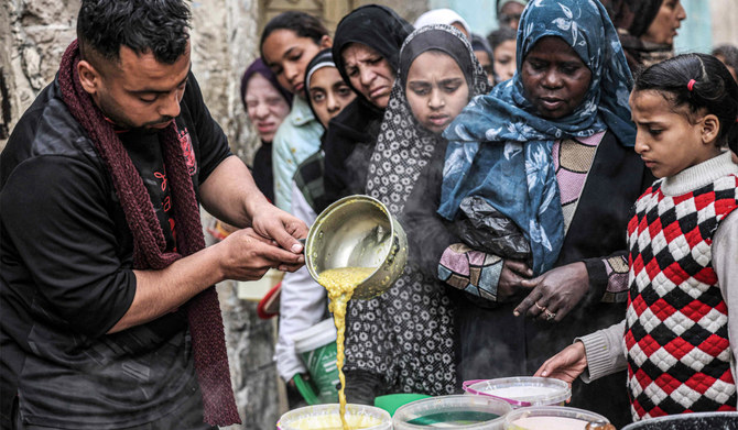 Displaced Palestinians queue to receive food donated by a charity organisation ahead of the fast-breaking 