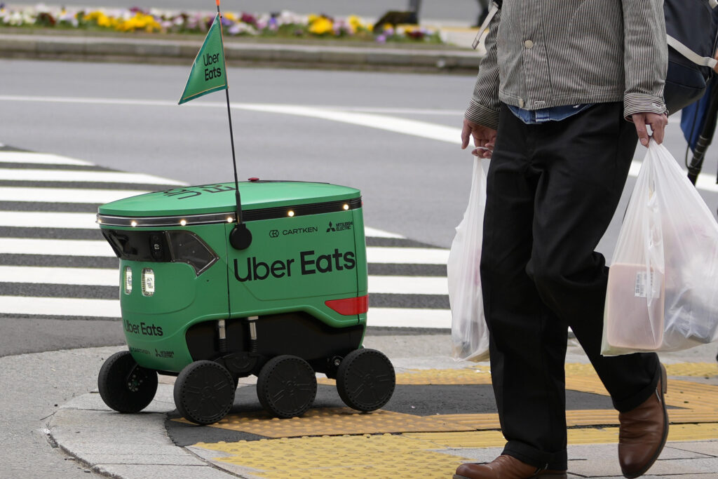 An Uber Eats food delivery robot waits to cross a street during its demonstration for media in Tokyo, Japan, Tuesday, March 5, 2024. Uber Eats Japan plans to launch the robot delivery service in a neighborhood in Tokyo, on Wednesday. (AP Photo/Shuji Kajiyama)