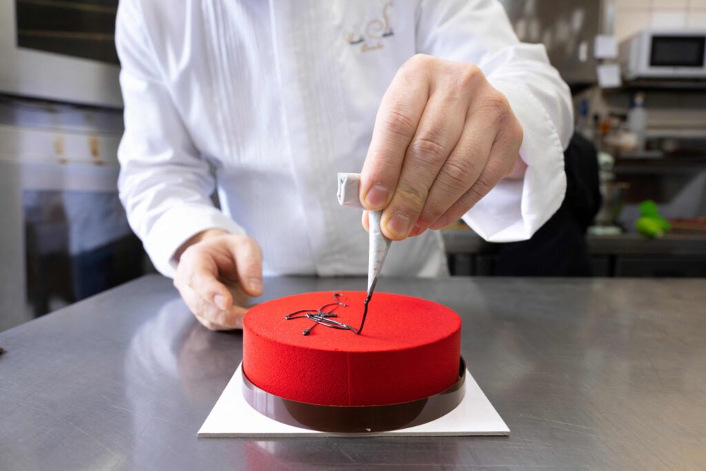 Japanese chocolatier Yasushi Sasaki spreads chocolate on a cake in his workshop in the Brussels commune of Woluwe-Saint-Pierre on March 14, 2024. (AFP)