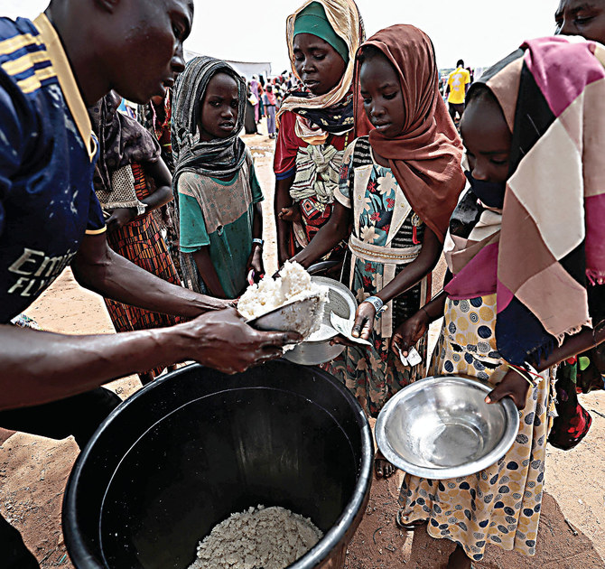 Sudanese people who fled the conflict in Geneina in Sudan's Darfur region, receive food from Red Cross volunteers in Ourang on the outskirts of Adre, Chad. (Reuters/File)