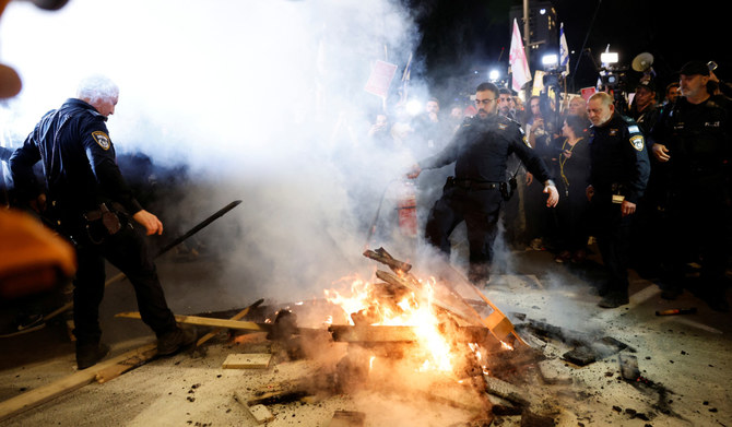 Police officers extinguish a fire at a protest against Israeli Prime Minister Benjamin Netanyahu's government and for the release of hostages kidnapped in the deadly October 7 attack on Israel by the Palestinian Islamist group Hamas from Gaza, in Tel Aviv, Israel, March 16, 2024. (REUTERS)