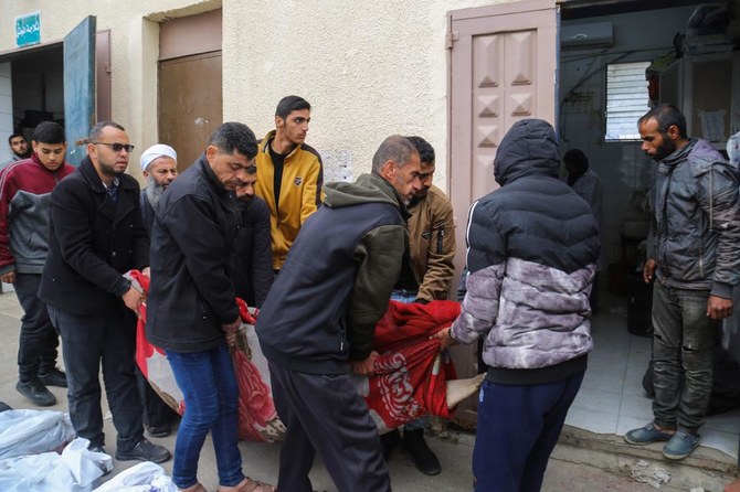 Palestinians mourn at the Al-Aqsa Martyrs Hospital in Deir Al-Balah next to bodies of victims pulled from the rubble of the Tabatibi family home on Mar, 16, 2024, following overnight Israeli bombardment west of the Nuseirat refugee camp in the central Gaza Strip. (AFP)