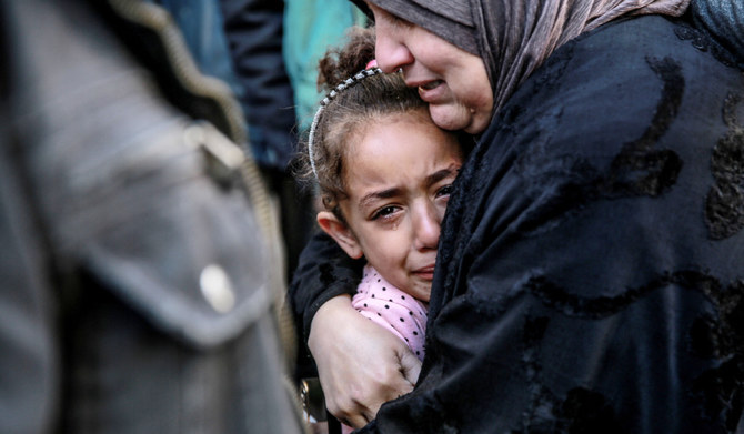 A Palestinian woman holds a child as they mourn their relatives killed in Israeli bombardment in front of the morgue of the Al-Shifa hospital in Gaza City on March 15, 2024, amid the ongoing conflict between Israel and the Palestinian Hamas movement. (AFP)