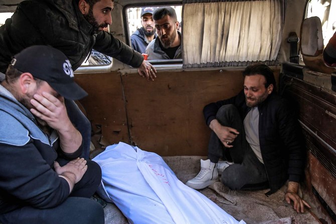 People mourn at Al-Shifa hospital in Gaza City, over the body of a Palestinian killed in an incident when residents rushed toward aid trucks, on February 29, 2024. (AFP)