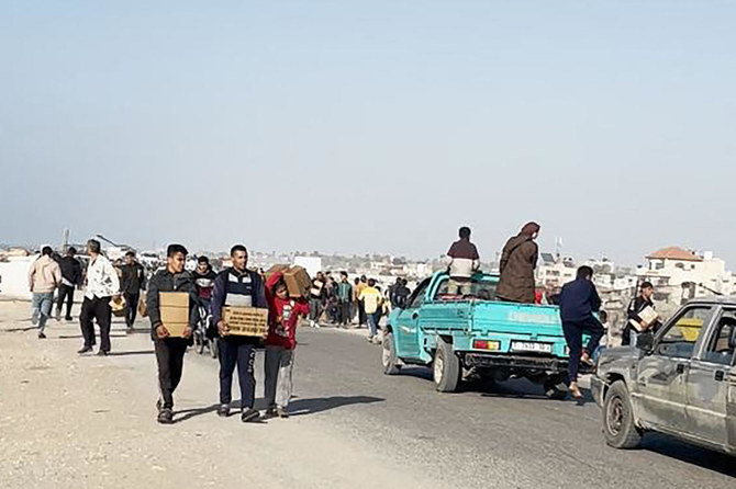 In this image grab from an AFPTV video, people carry food parcels that were air-dropped from US aircrafts above a beach in the Gaza Strip, on Mar. 2, 2024. (AFP)