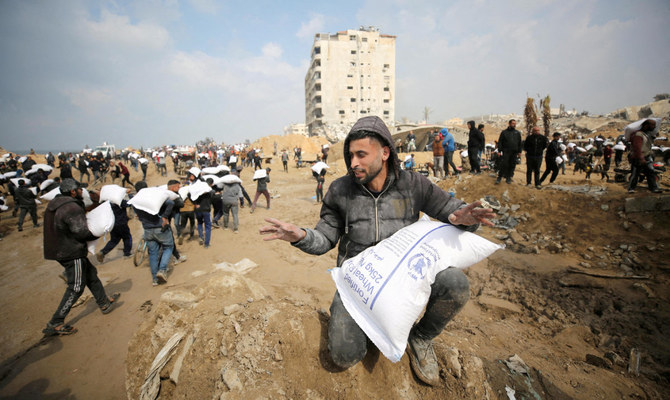 Palestinians carry bags of flour they grabbed from an aid truck near an Israeli checkpoint, as Gaza residents face crisis levels of hunger, amid the ongoing conflict between Israel and Hamas, in Gaza City. (Reuters)