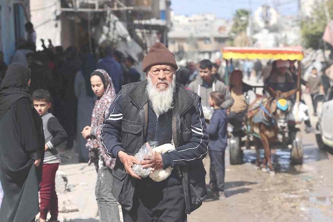 Above, a resident carries a small amount of supplies from a specialized shop at the Bureij refugee camp in the central Gaza Strip on March 6, 2024. (AFP)