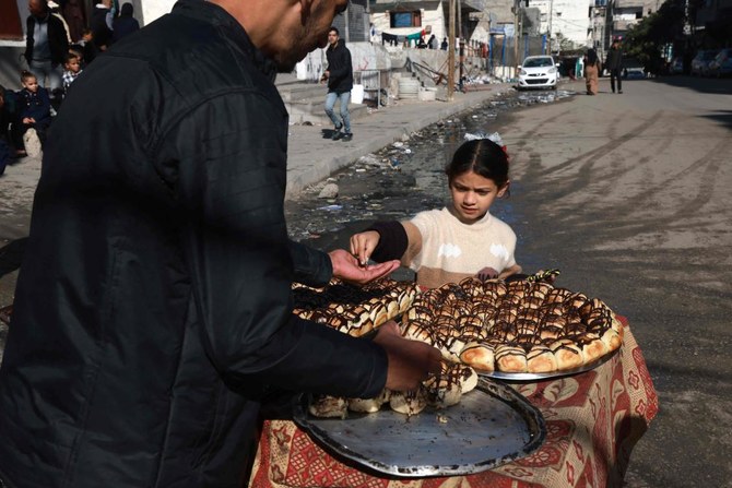 Palestinian children buy pastries from a street vendor in Rafah in the southern Gaza Strip on Mar. 5, 2024. (AFP)