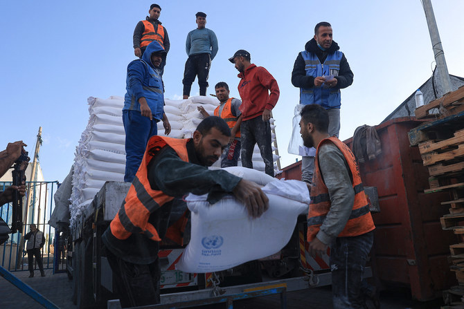 Palestinians receive bags of flour at the UNRWA distribution center in the Rafah refugee camp in the southern Gaza Strip. (File/AFP)