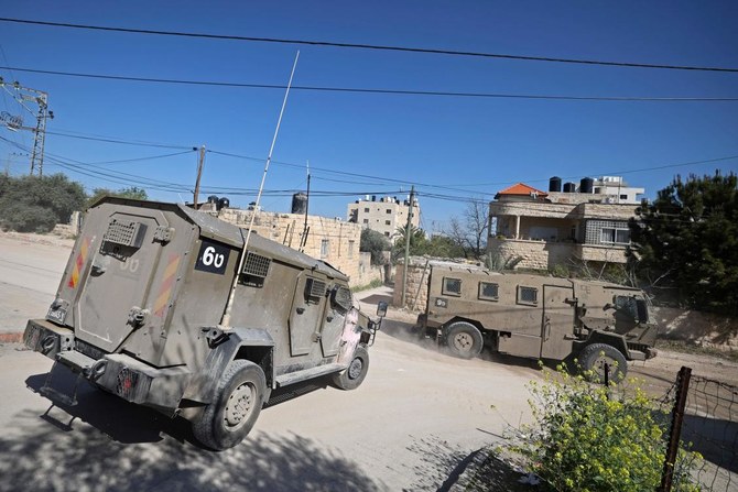 Israeli military vehicles patrol along a street during a raid at the Jenin refugee camp area in the occupied West Bank on March 12, 2024. (AFP)