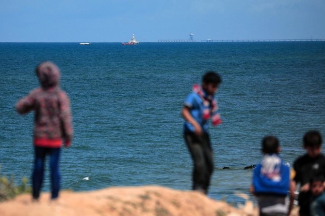 Palestinian children gather on the beach as the Open Arms maritime vessel that set sail from Larnaca in Cyprus carrying humanitarian aid approaches the coast of Gaza City on Mar. 15, 2024. (AFP)