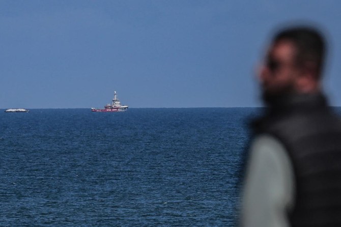 A Palestinian man watches as the Open Arms maritime vessel that set sail from Larnaca in Cyprus carrying humanitarian aid, approaches the coast of Gaza City on Mar. 15, 2024. (AFP)