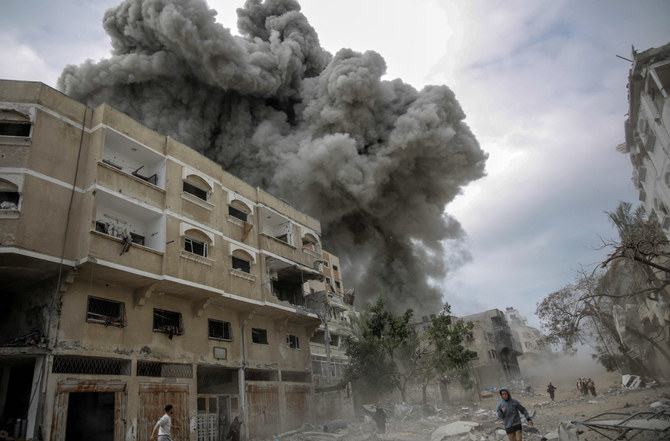 Palestinians rush for cover as smoke billows after Israeli bombardment in central Gaza City on March 18, 2024, amid the ongoing battles between Israel and the militant group Hamas. (AFP)