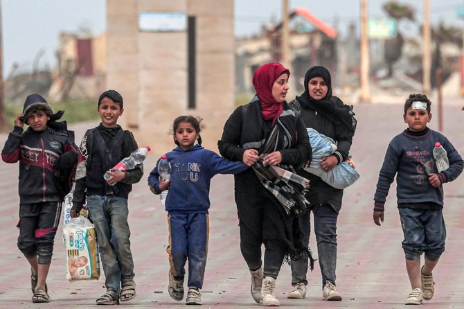 Displaced Palestinians fleeing from the area in the vicinity of Gaza City's al-Shifa hospital walk along the coastal highway as they arrive at the Nuseirat refugee camp in the central Gaza Strip. (File/AFP)