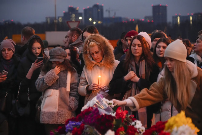 People lay flowers and light candles standing next to the Crocus City Hall in Moscow on March 23, 2024. (AP)