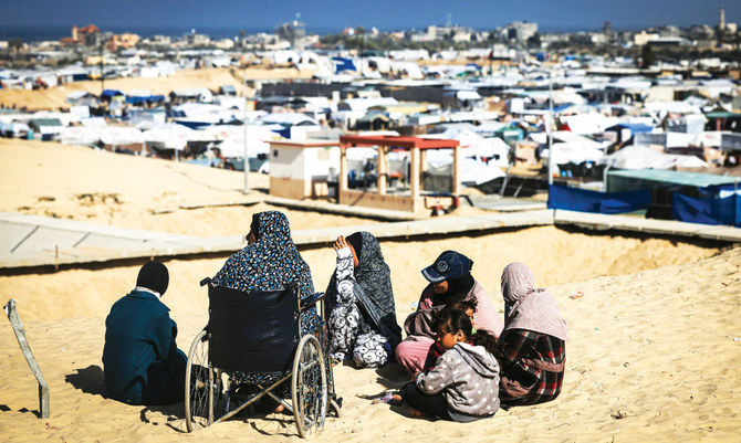 Displaced Palestinian women and gather on a sand dune above a makeshift camp on the Egyptian border, west of Rafah in the southern Gaza Strip on January 14, 2024. (AFP/File)