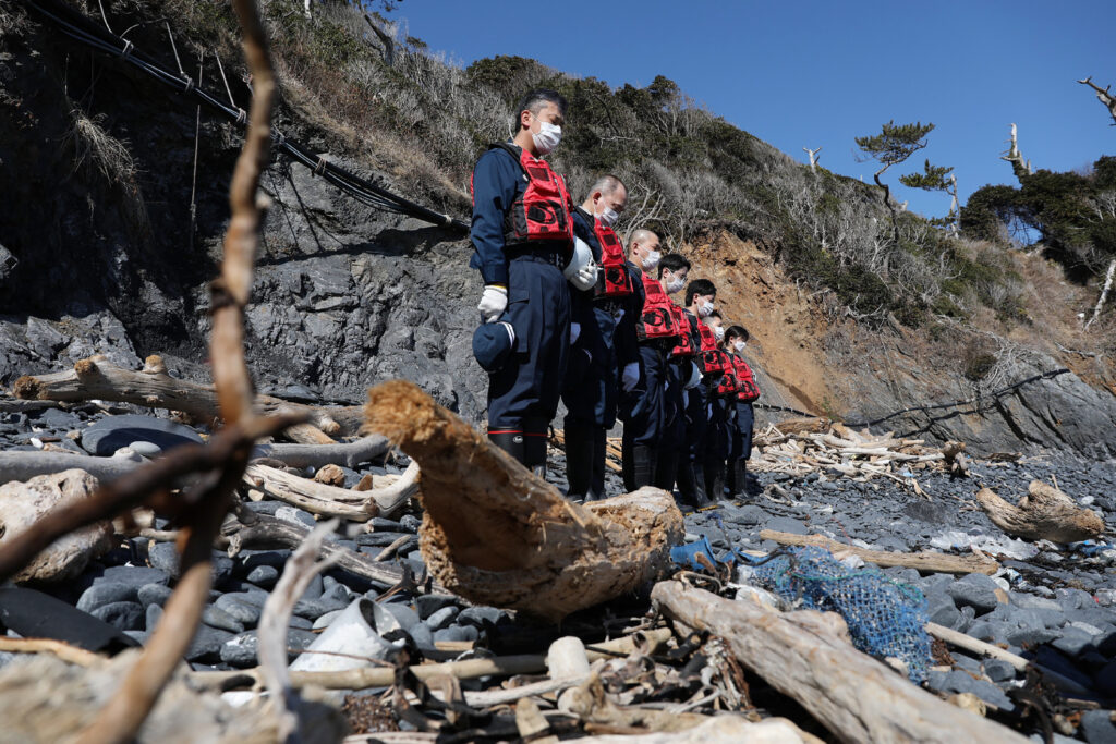 Police officers offer silent prayers to earthquake and tsunami victims in Minamisanriku, Miyagi prefecture on March 10, 2022, one day before the 11th anniversary of the Great East Japan earthquake which triggered a tsunami and devastating nuclear meltdown. (AFP)