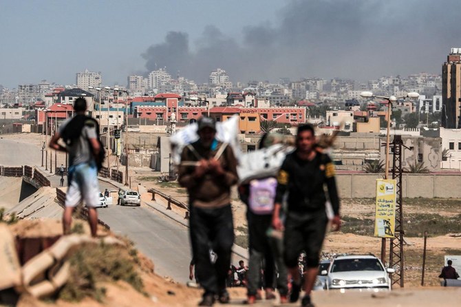 Smoke rises above buildings during Israeli bombardment as people fleeing the Al-Shifa hospital compound and its vicinity in Gaza City, reach the central part of the Gaza Strip on Mar. 21, 2024. (AFP)