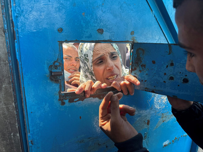 A Palestinian woman speaks with a worker as she waits to receive aid from an UNRWA distribution center which was hit in an Israeli strike in Rafah on Mar. 13, 2024. (Reuters)