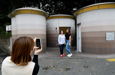 Foreign tourists get their photos taken in front of a public toilet which was redesigned as part of a project to transform public toilets into restrooms that can be used comfortably by everyone, during a Tokyo Toilet Shuttle Tour, at Shibuya ward, in Tokyo, Japan April 4, 2024. (Reuters)