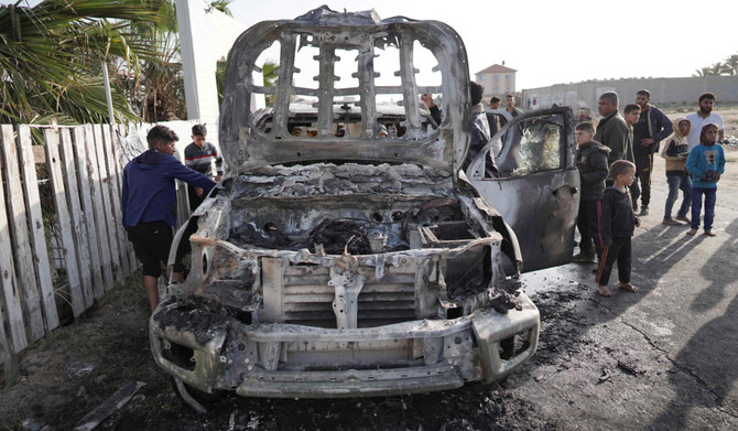 People gather around the car of the US-based aid group World Central Kitchen that was hit by an Israeli strike the previous day in Deir al-Balah in the central Gaza Strip on April 2, 2024, amid the ongoing battles between Israel and the Palestinian militant group Hamas. (AFP)