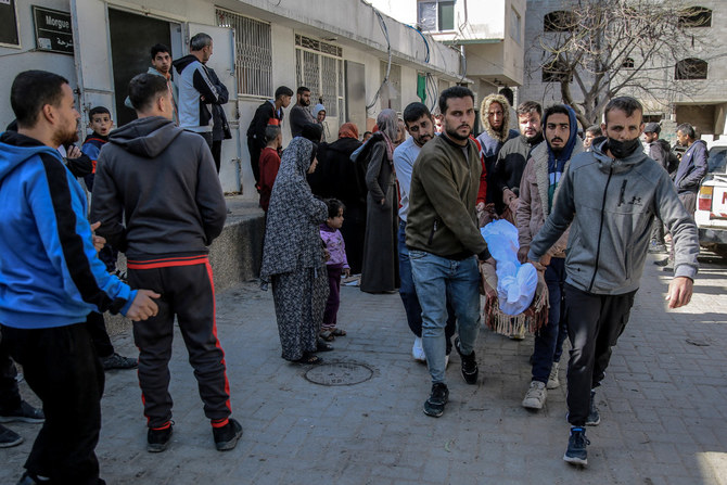 Palestinians carry away the body of a man killed in Israeli bombardment from the morgue of the Al-Shifa hospital in Gaza City on March 15, 2024, amid the ongoing conflict between Israel and the Palestinian Hamas movement. (AFP)