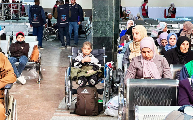 A young Palestinian cancer patient, center, evacuated from the war-torn Gaza Strip, sits in a wheelchair in the arrivals hall on the Egyptian side of the Rafah border crossing in Sinai province on his way for treatment in the UAE. (AFP)