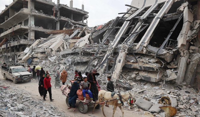 Palestinians walk past damaged buildings in Khan Yunis on April 8, 2024 after Israel pulled its ground forces out of the southern Gaza Strip. (AFP)