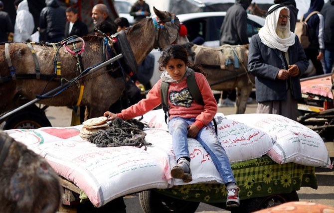 A Palestinian girl sits on bags of flour distributed by the UN Relief and Works Agency (UNRWA), amid the ongoing conflict between Israel and Hamas, Rafah, southern Gaza Strip, Jan. 29, 2024. (Reuters)