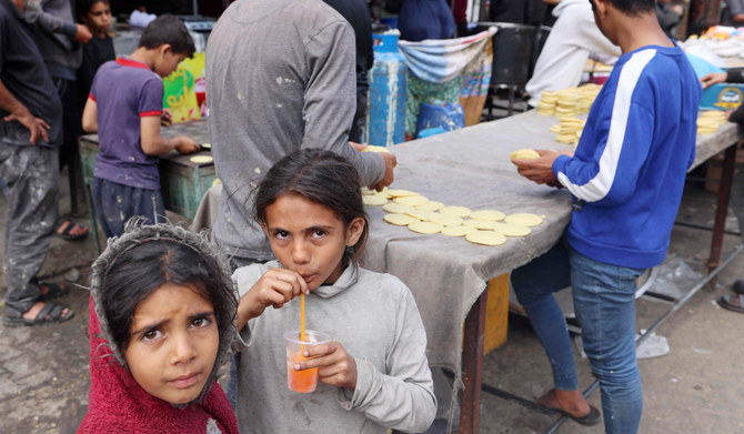 Palestinian children look on as vendors make seasonal sweets in a market, ahead of Eid al-Fitr celebrations which conclude the Muslim holy fasting month of Ramadan, in Rafah in the southern Gaza Strip on April 5, 2024 amid the ongoing conflict between Israel and the militant group Hamas. (AFP)