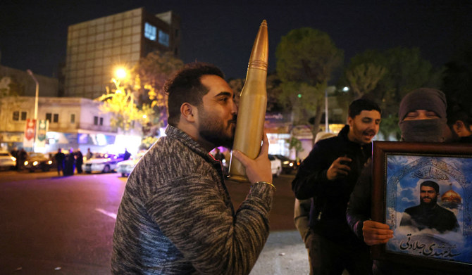 A demonstrator kisses a bullet shell replica as others gather at Palestine Square in Tehran on April 14, 2024, after Iran launched a drone and missile attack on Israel. (AFP)