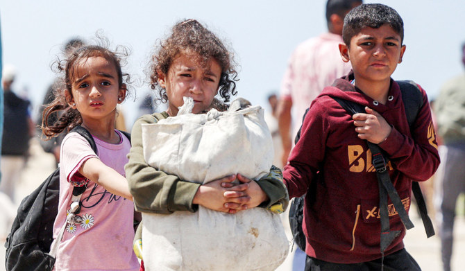 Children walk with other displaced Palestinians taking the coastal Rashid road to return to Gaza City as they pass through Nuseirat in the central Gaza Strip on Friday. (AFP)