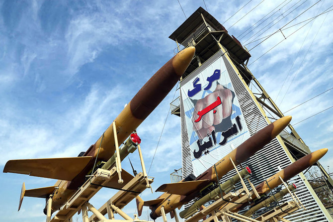 Iranian-made Karrar drones are displayed next to a banner reading in Persian 