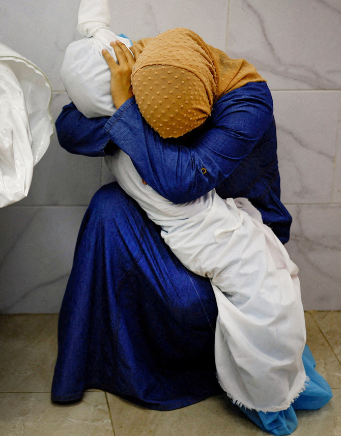 Palestinian woman Inas Abu Maamar, 36, embraces the body of her 5-year-old niece Saly, who was killed in an Israeli strike, at Nasser hospital in Khan Younis in the southern Gaza Strip, October 17, 2023. (REUTERS)