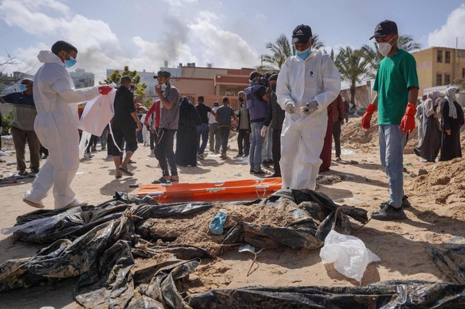 Palestinian health workers stand next to unearthed bodies buried by Israeli forces in Nasser hospital compound in Khan Yunis in the southern Gaza Strip. (File/AFP)